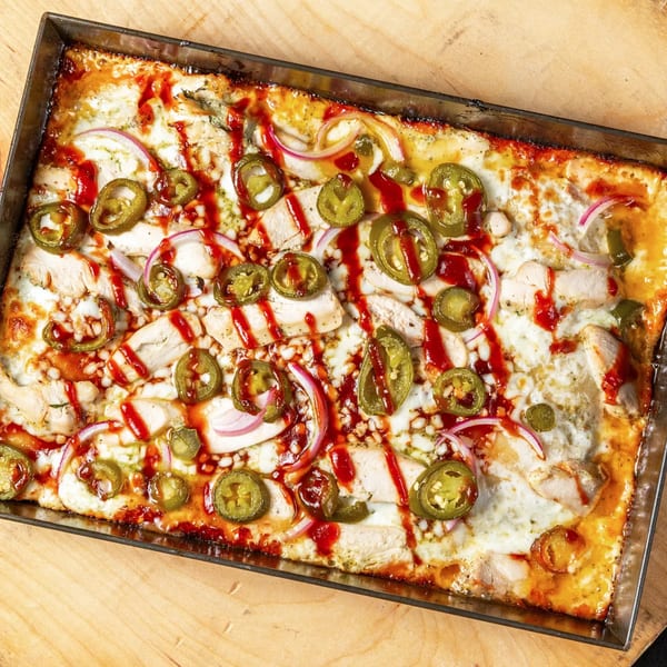 Main Street Pizza's rectangular pizza with chicken, red onions, jalapeños, and BBQ sauce drizzle.