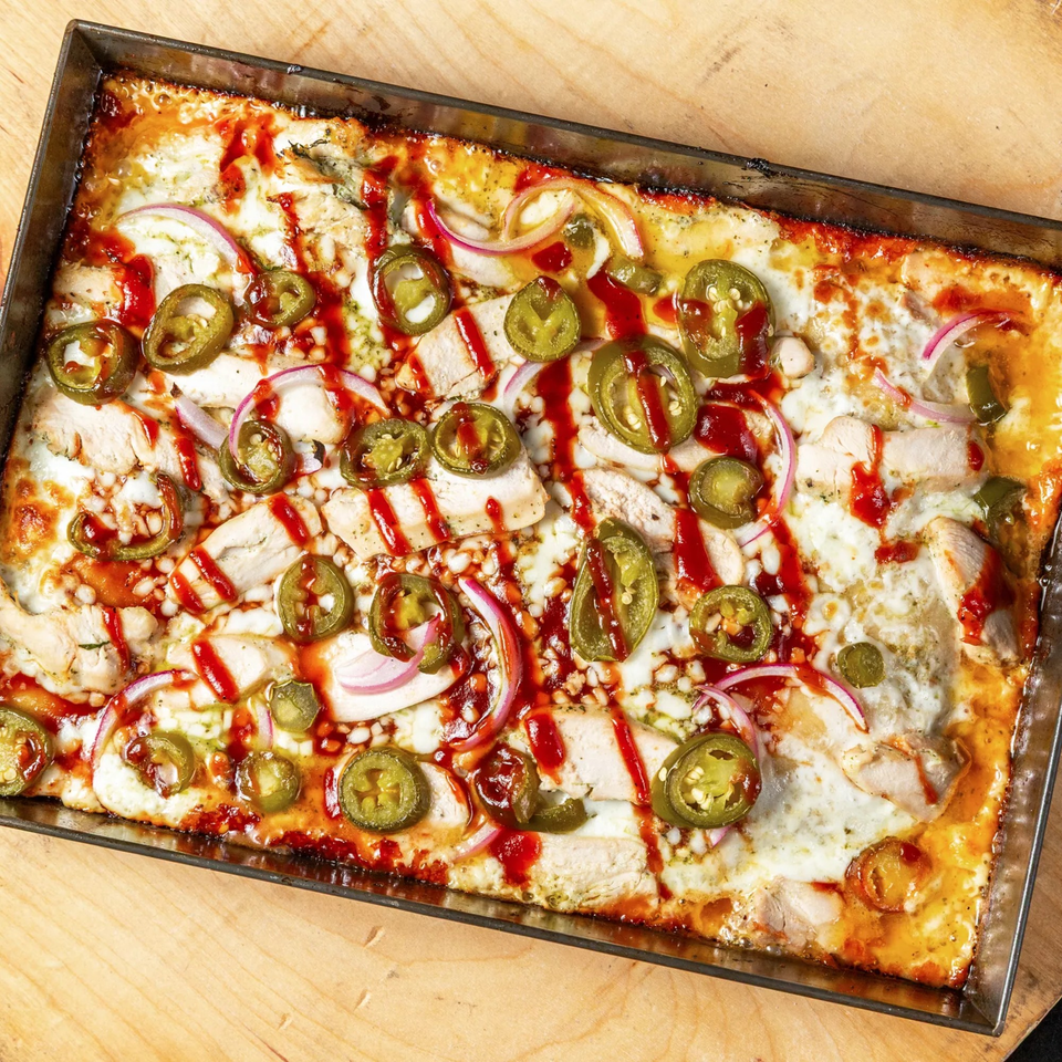 Main Street Pizza's rectangular pizza with chicken, red onions, jalapeños, and BBQ sauce drizzle.